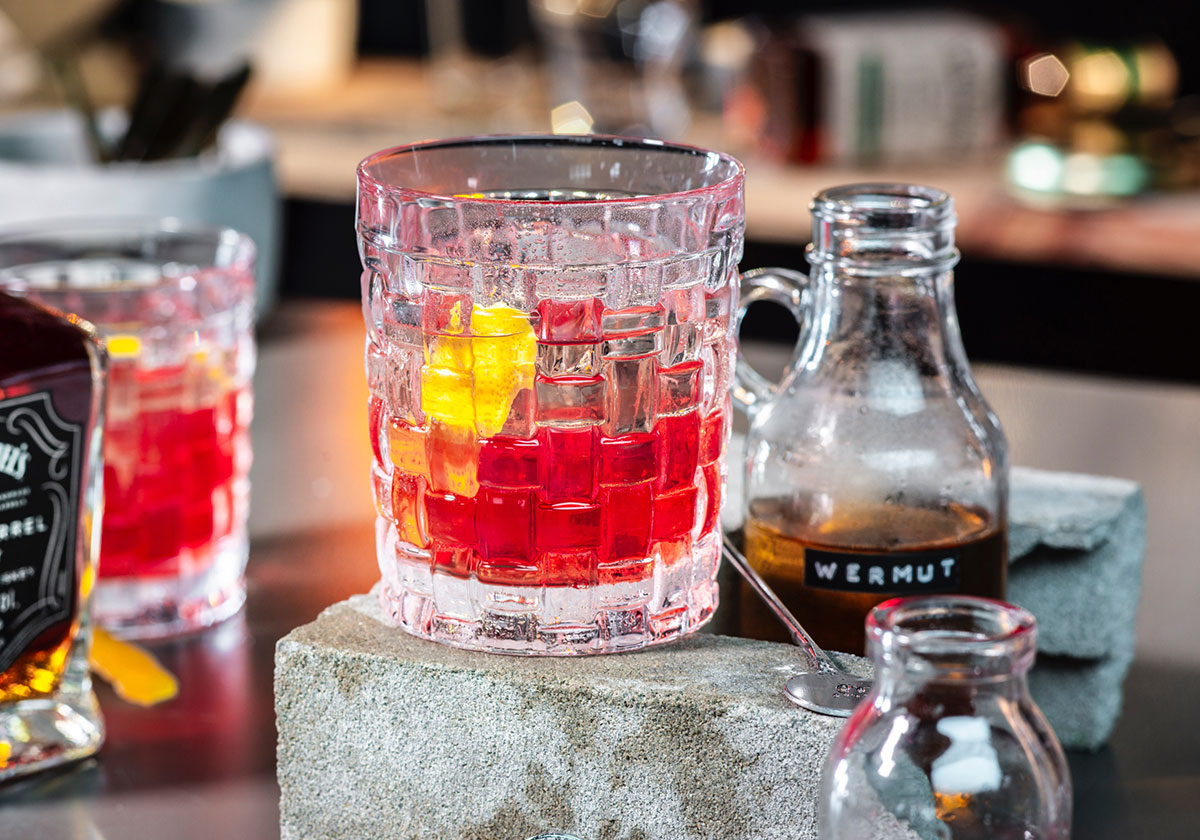 Lågt cocktailglas med röd drink på bardisk