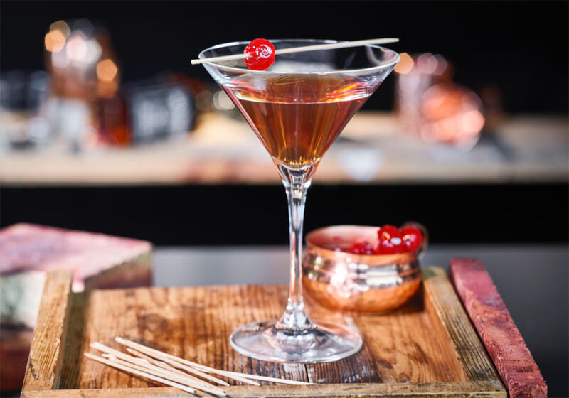 Martiniglas med drinken Manhattan på bardisk 