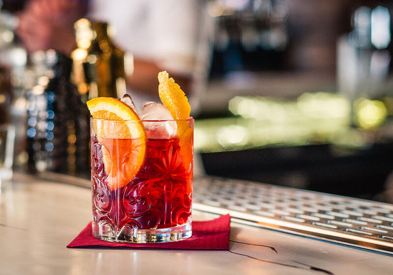 Negroni i ett lågt cocktailglas på en bardisk. 